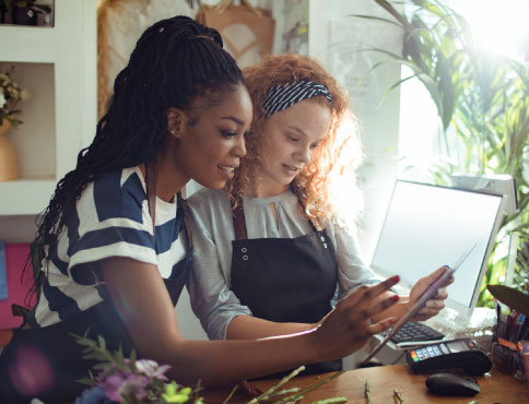 Two women in aprons looking at a tablet together