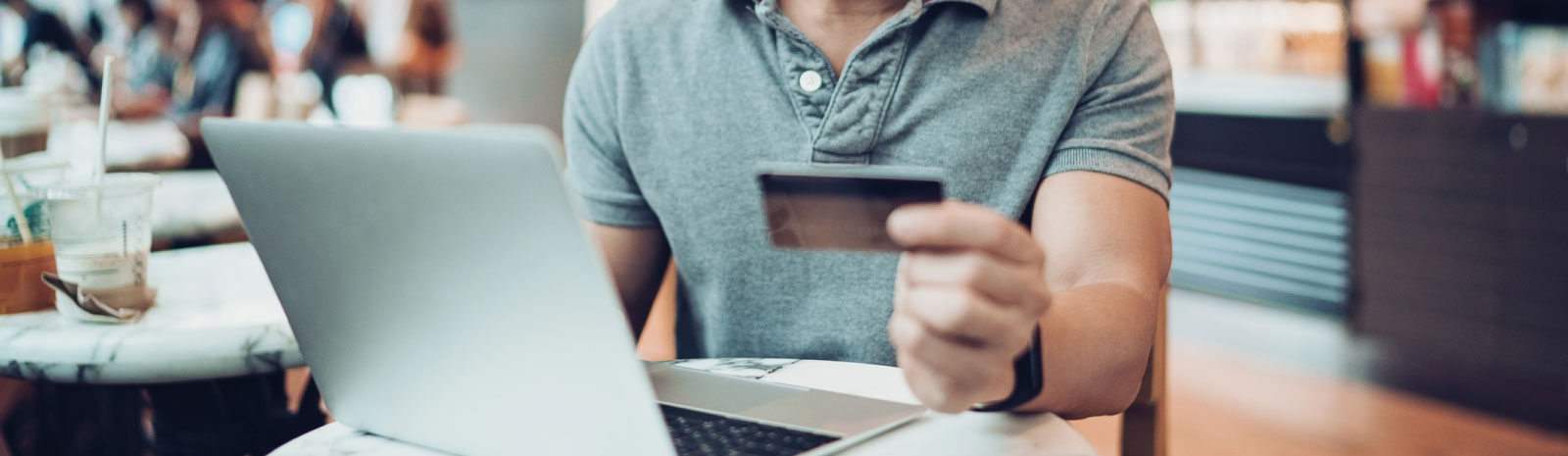 Man holding credit card while sitting at the computer.