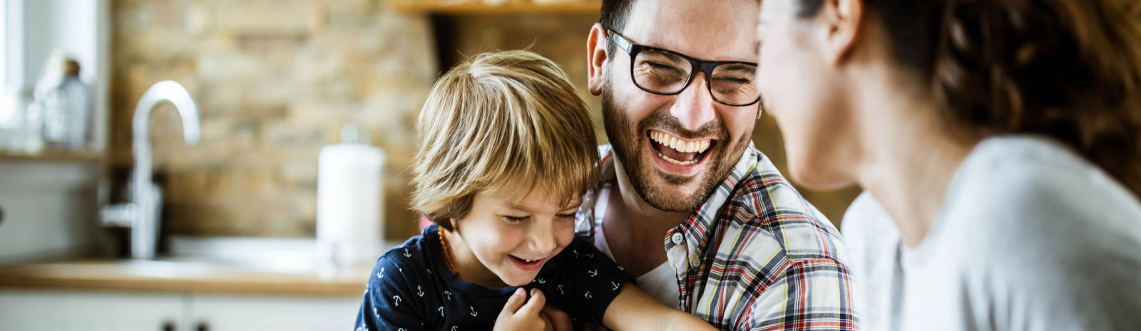 Father, son, and mother laugh at the dining table.