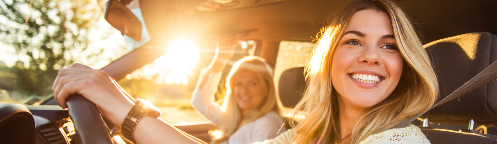 A woman joyfully sits in the driver's seat of the car.