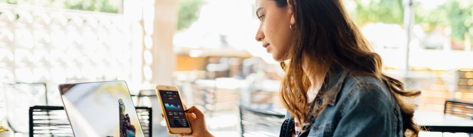 Woman looking at her phone while sitting at a computer.